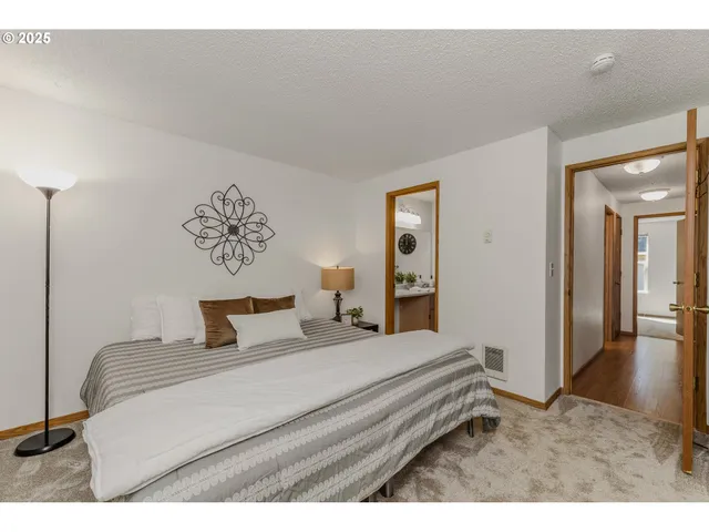 a bedroom with a bed and a lamp on dresser