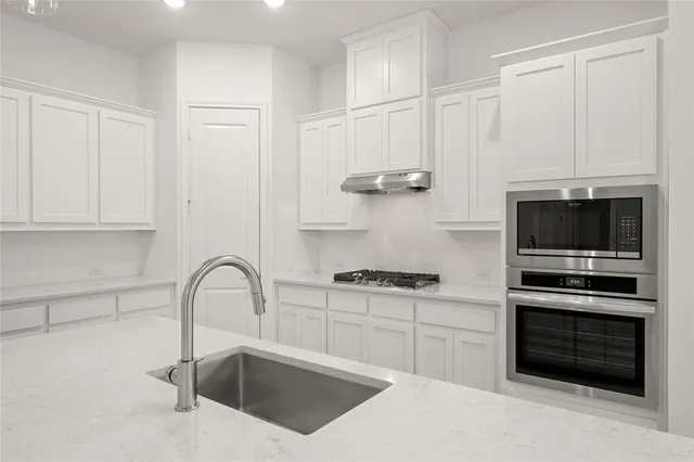 a kitchen with white cabinets a sink and stainless steel appliances