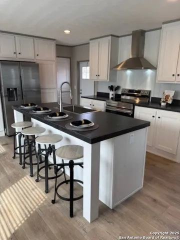 a kitchen with stainless steel appliances granite countertop a stove a sink a refrigerator and white cabinets