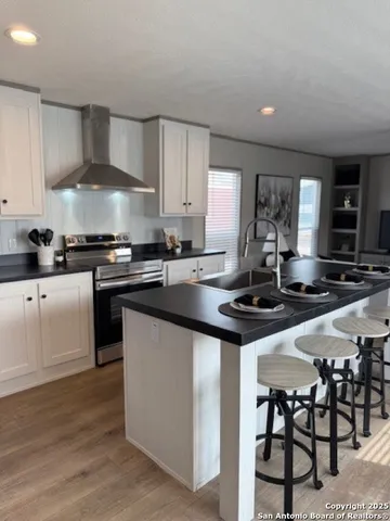 a kitchen with stainless steel appliances a sink a stove a table and chairs