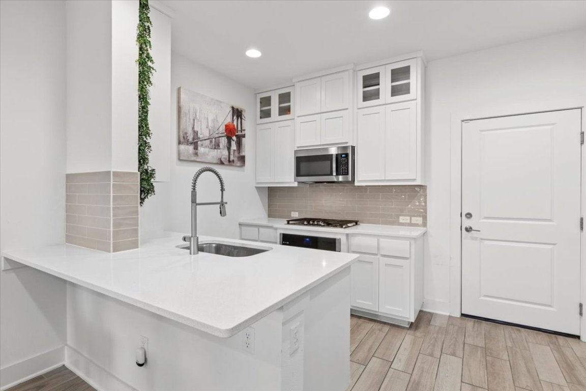 2516 Simond Avenue, Unit D Austin, TX 78723 - Photo 13 of 31 Kitchen featuring, tasteful backsplash, white cabinetry, and stainless steel microwave