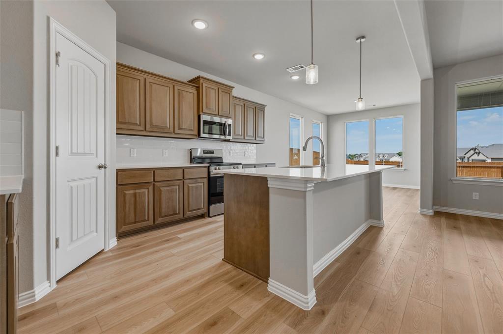 1201 Colca Drive Springtown, TX 76082 - Photo 12 of 32 Wood-finish flooring throughout, kitchen island with countertop, stainless steel appliances, recessed lighting, and ample natural light