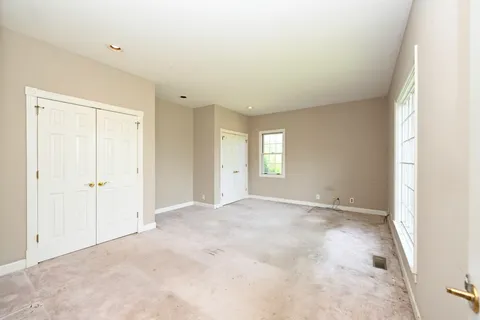 a view of an empty room with window and closet area