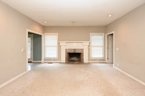 a view of an empty room with a fireplace and a window