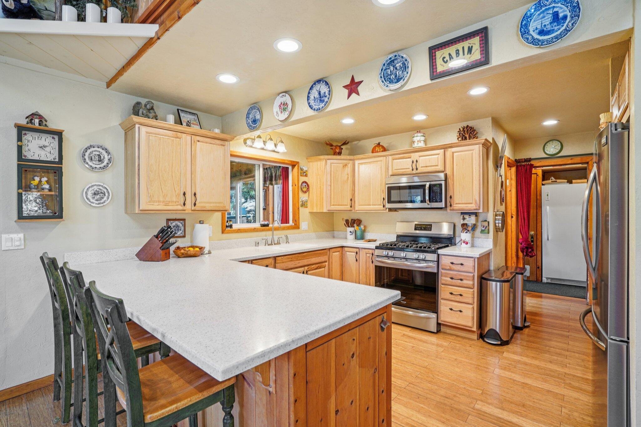 25361 Skyline Way Idyllwild, CA 92549 - Photo 12 of 42 a kitchen with stainless steel appliances granite countertop a stove refrigerator and a dining table with wooden floor