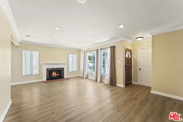 a view of an empty room with wooden floor fireplace and a window