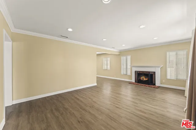 a view of an empty room with wooden floor fireplace and a window