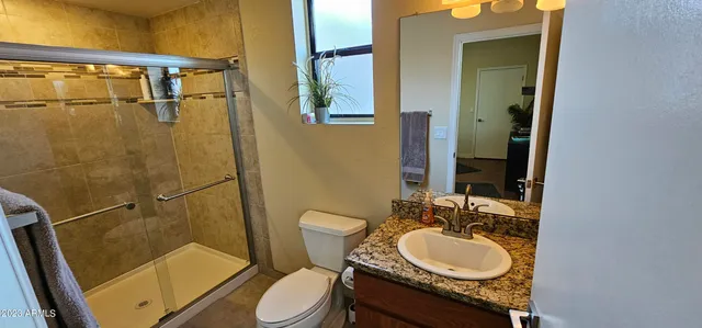 a bathroom with a granite countertop sink toilet a mirror and shower