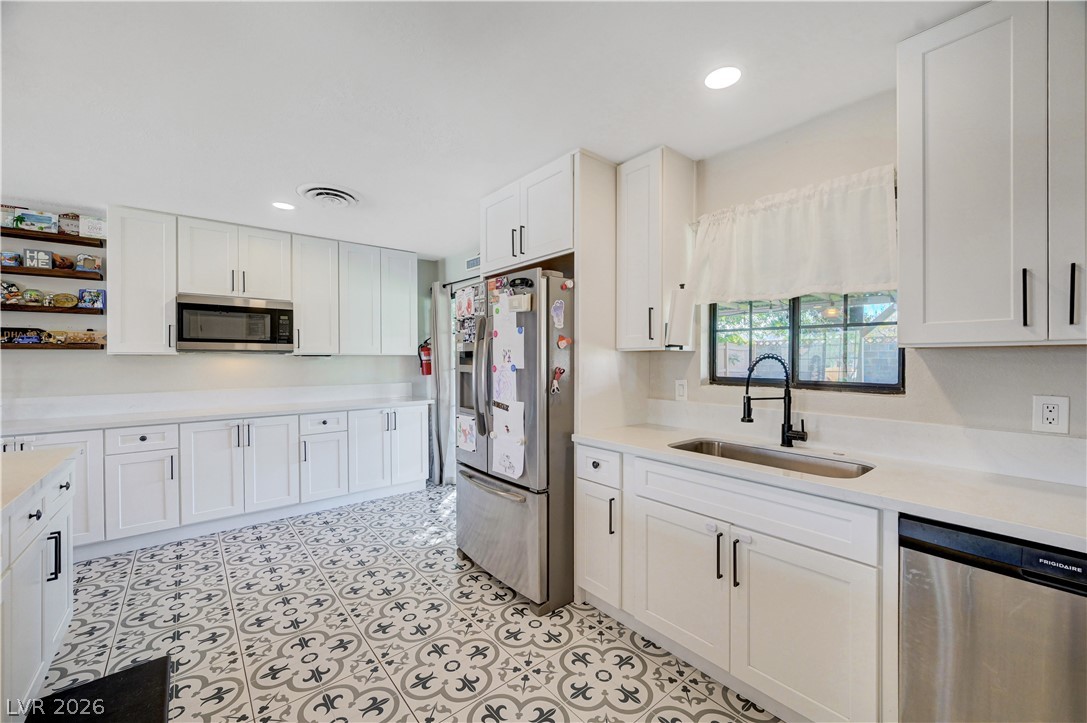 1331 Pinto Road Boulder City, NV 89005 - Photo 22 of 46 A well-lit kitchen with sleek white cabinetry and decorative tiled flooring.