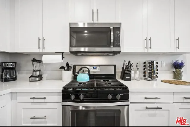 a kitchen with stainless steel appliances granite countertop white cabinets and a stove a oven with white countertops