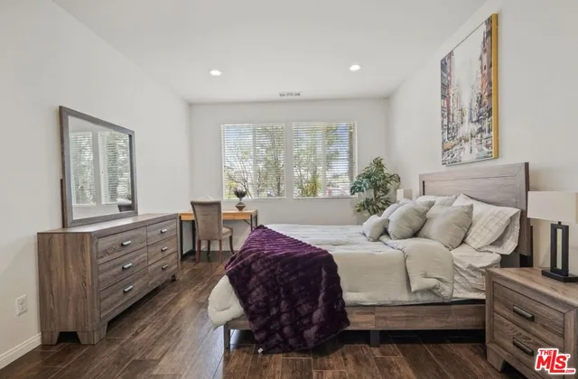 a bedroom with a bed and a dresser next to a window