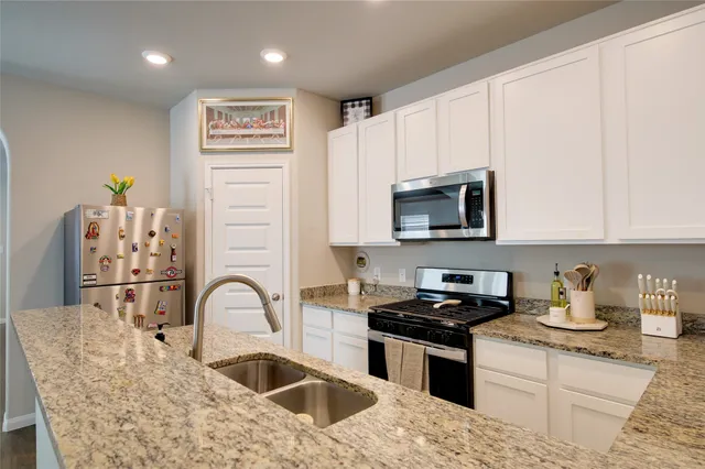 a kitchen with stainless steel appliances granite countertop a stove a sink and a microwave
