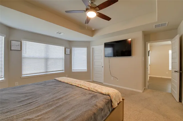 a bedroom with a large bed and a flat tv screen on dresser