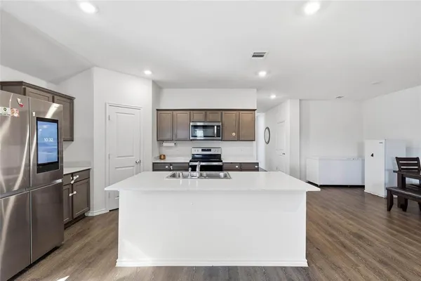 a kitchen with stainless steel appliances a microwave a stove a refrigerator sink and cabinets