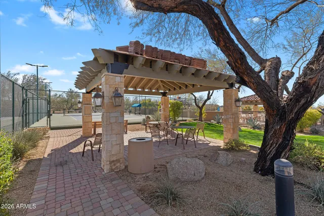 a view of a patio with table and chairs under an umbrella with a large tree