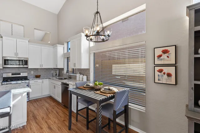 a kitchen with stainless steel appliances granite countertop a stove top oven a sink dishwasher and a dining table with wooden floor