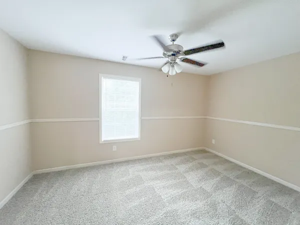 an empty room with a window and a fan