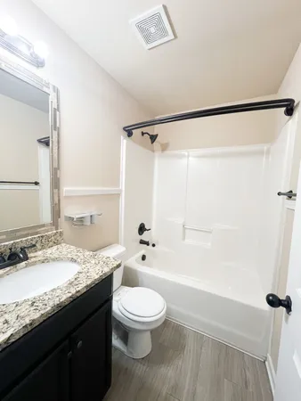 a bathroom with a granite countertop sink toilet a large mirror a shower and a bathtub