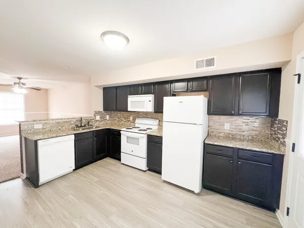 a kitchen with granite countertop a refrigerator and a stove top oven