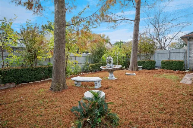 a backyard of a house with table and chairs plants and large trees