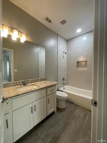 a bathroom with a granite countertop sink a toilet and bathtub