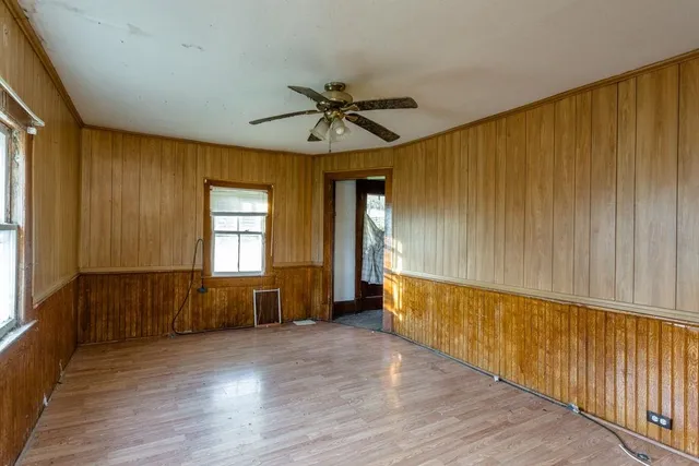 a view of an empty room with a window and wooden floor