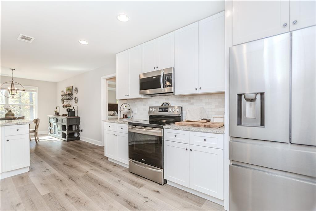 43 Water Lily Way Pendergrass, GA 30567 - Photo 16 of 71 a kitchen with stainless steel appliances white cabinets and wooden floors