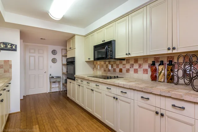 a kitchen with granite countertop white cabinets and a wooden floor
