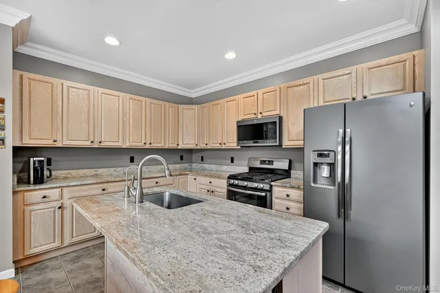 a kitchen with granite countertop a refrigerator a sink a stove a microwave and island