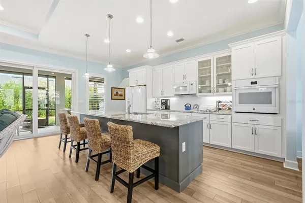 a kitchen with kitchen island granite countertop a stove a sink a dining table and chairs with wooden floor