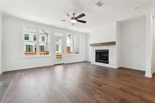an empty room with wooden floor fireplace and windows