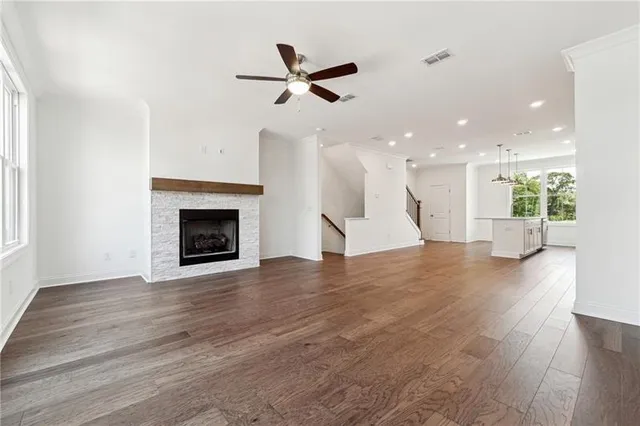a view of a livingroom with a ceiling fan wooden floor and a kitchen