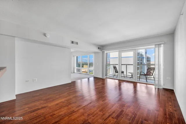 a view of empty room with wooden floor and floor to ceiling window