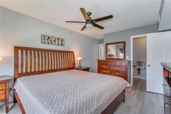 a bedroom with a bed and dresser with wooden floor