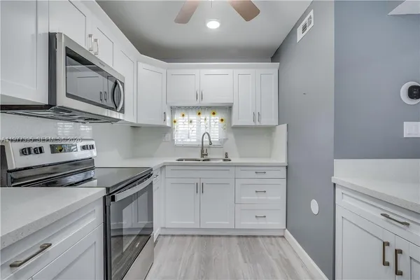 a kitchen with white cabinets stainless steel appliances and sink