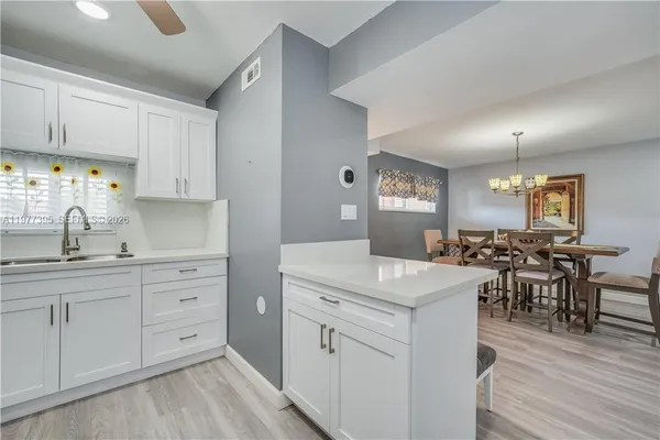 a kitchen with white cabinets appliances and wooden floor