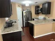 a kitchen with kitchen island granite countertop stainless steel appliances a sink stove refrigerator and a microwave