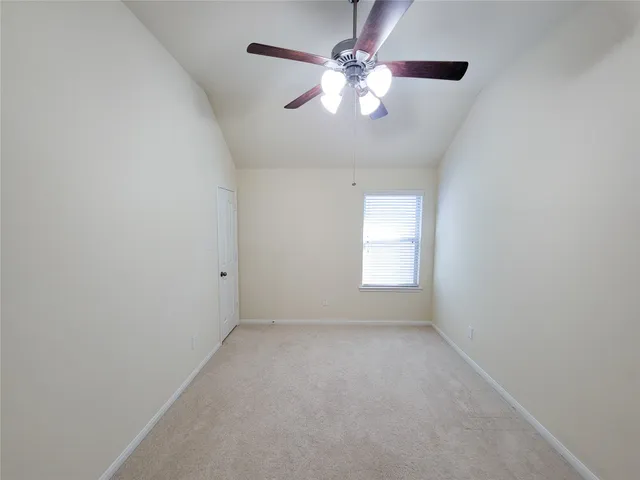 an empty room with a chandelier fan and windows