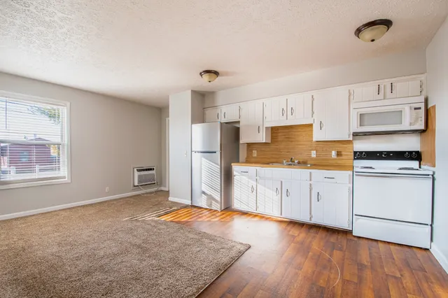 a kitchen with granite countertop white cabinets and white appliances