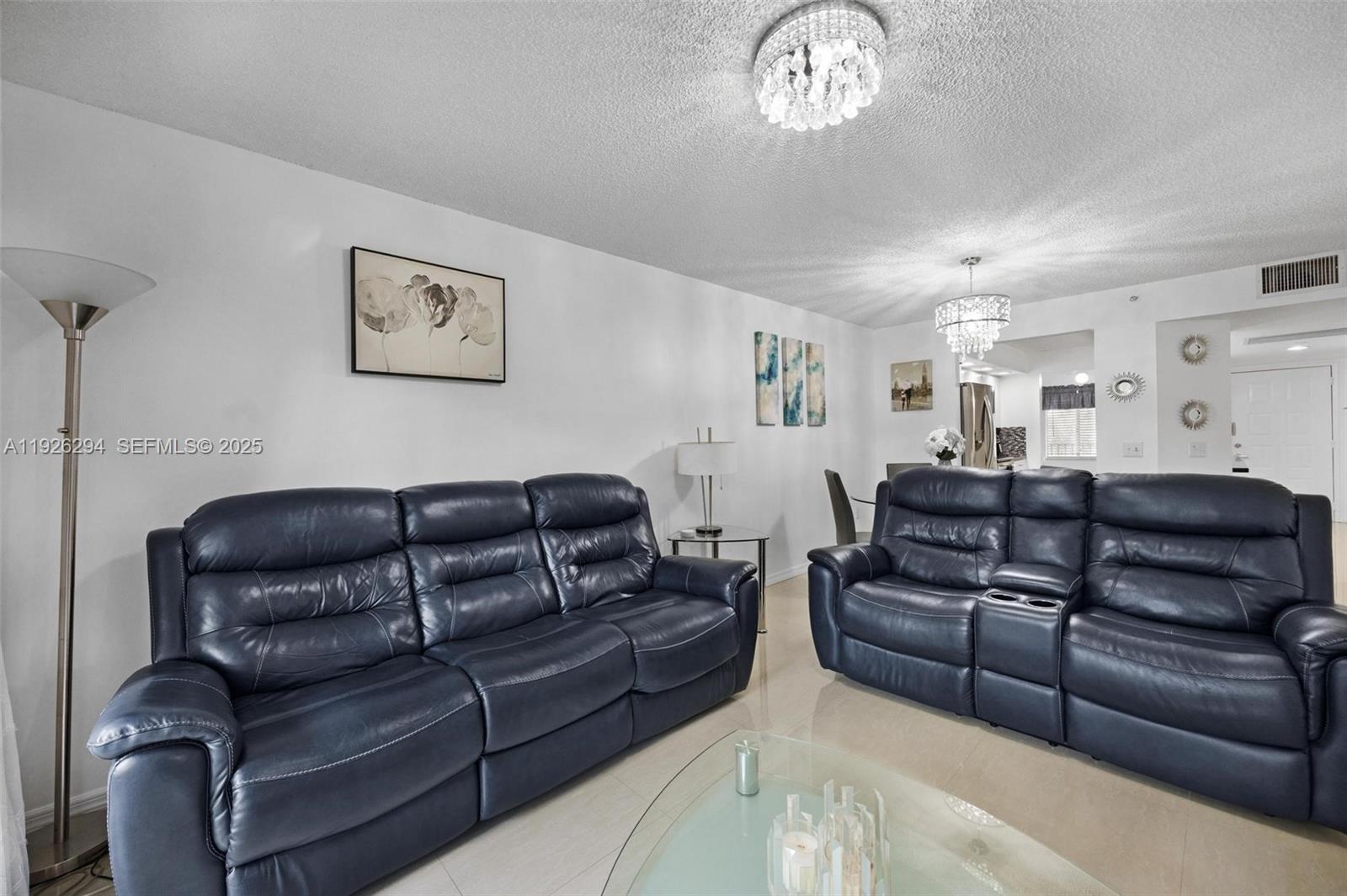 900 Southwest 142nd Avenue, Unit 306L Pembroke Pines, FL 33027 - Photo 27 of 34 a large living room with couches a fireplace and a chandelier