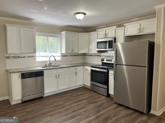 a kitchen with granite countertop white cabinets and stainless steel appliances