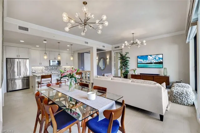 a living room with furniture a chandelier and kitchen view