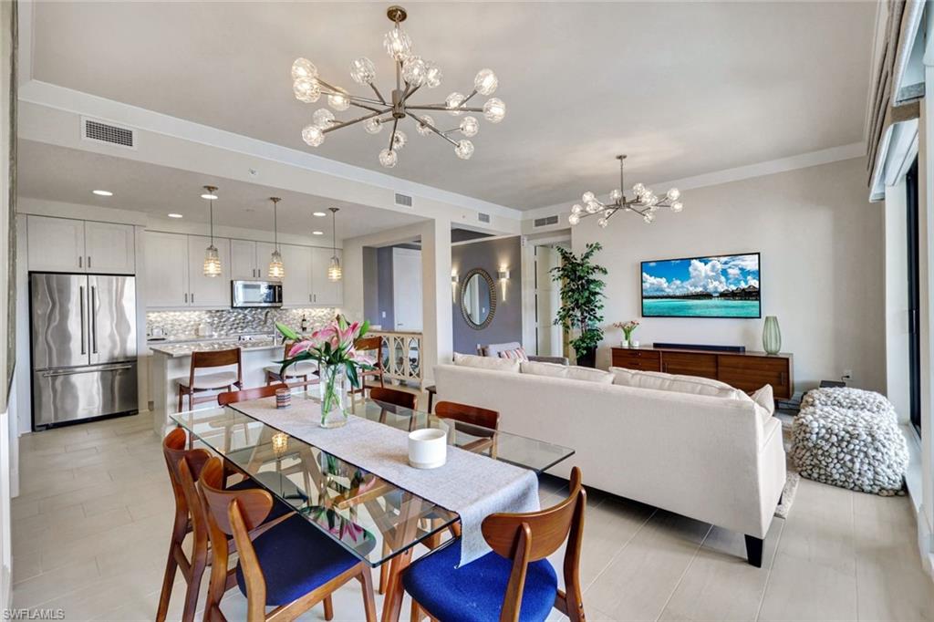 a living room with furniture a chandelier and kitchen view