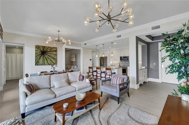 a living room with furniture kitchen view and a chandelier