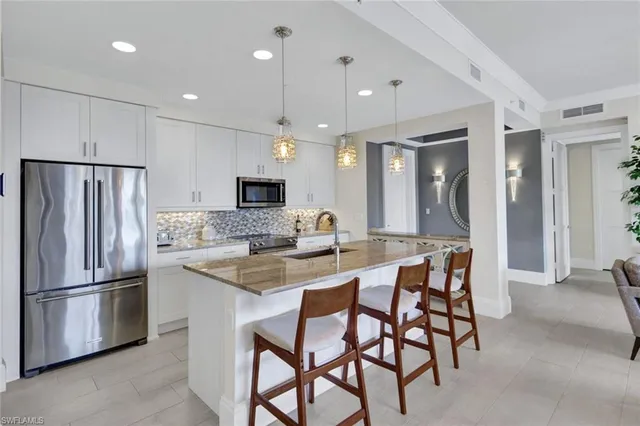 a kitchen with stainless steel appliances granite countertop a sink a stove a refrigerator and island