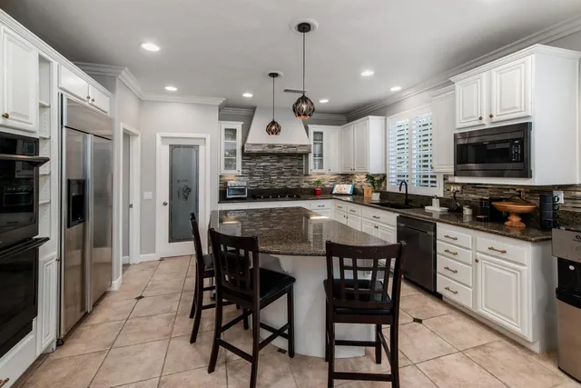 a kitchen with stainless steel appliances granite countertop a stove a sink a microwave a refrigerator and cabinets