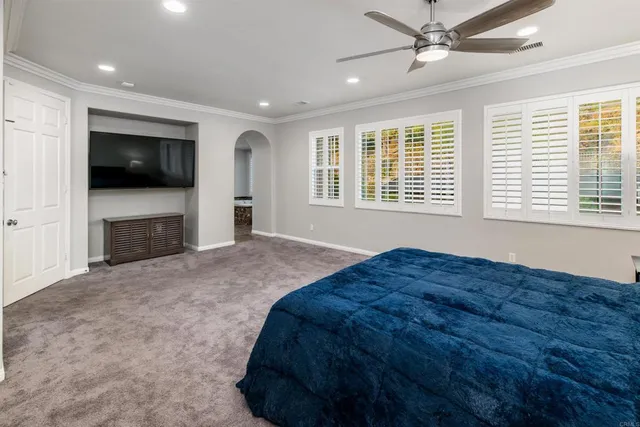 a bed sitting in a spacious bedroom next to a window and a television