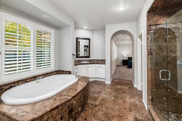 a bathroom with a tub a sink a mirror and a shower