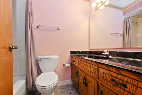 a bathroom with a granite countertop toilet sink and mirror