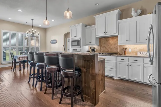 a kitchen with stainless steel appliances granite countertop a table chairs refrigerator and sink